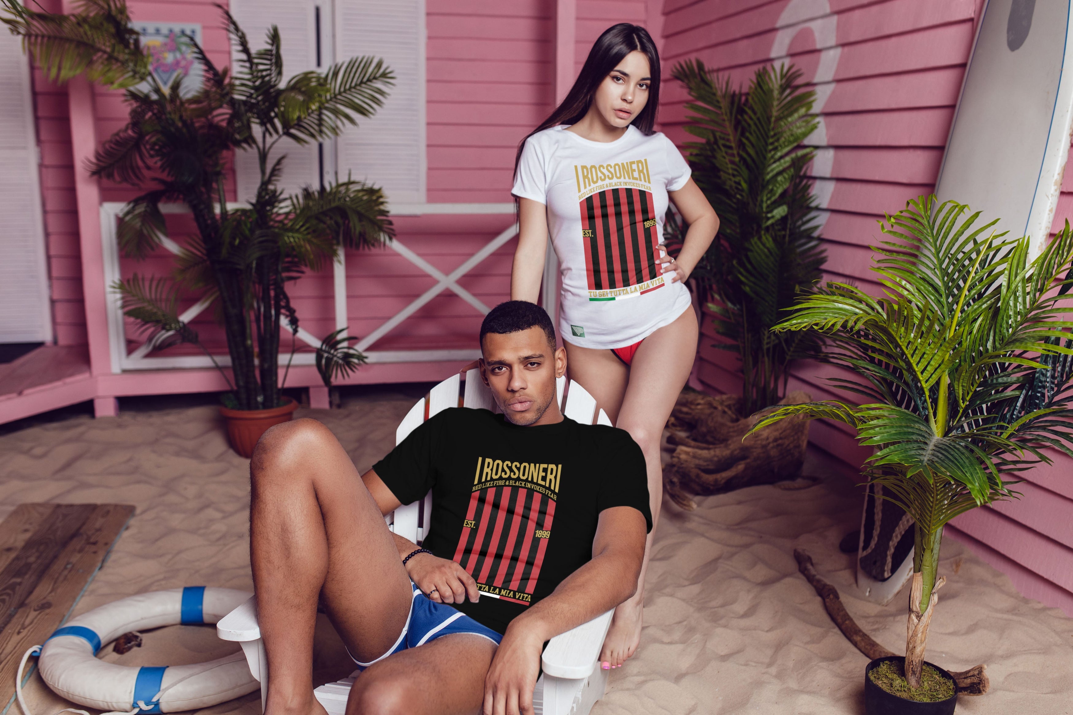 Two people wearing 'Rasserman' t-shirts in a beach-themed setting with pink walls and plants.